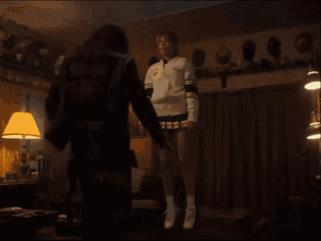a woman in a cheerleader outfit is standing on a chair in a living room