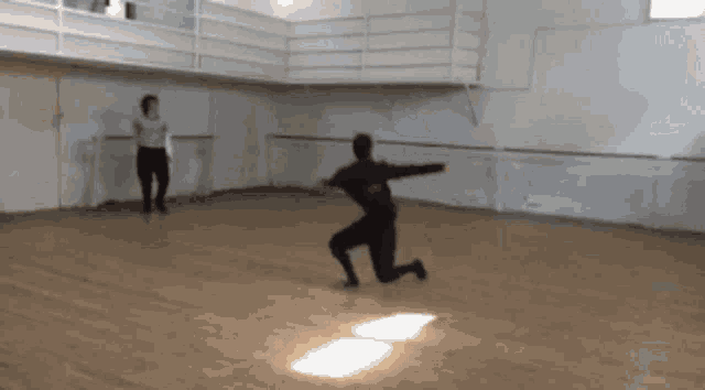 a man is kneeling down in a dance studio with a woman standing behind him