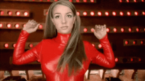britney spears is wearing a red leather outfit and flexing her muscles .