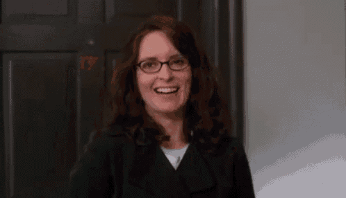 a close up of a woman wearing glasses and a black jacket smiling .