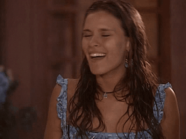 a woman in a blue dress is crying and covering her mouth with her hand .