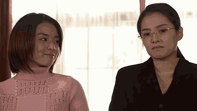 two women standing next to each other one wearing glasses