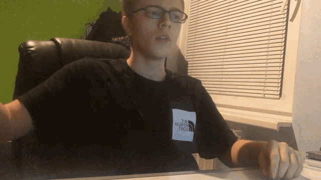 a young man wearing glasses and a north face shirt