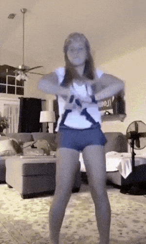 a woman dancing in a living room with a sign that says emoji