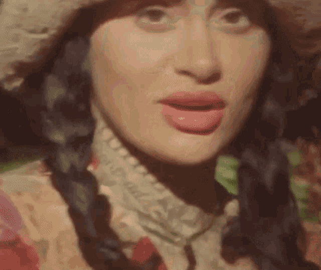 a close up of a woman wearing a hat and a braided hair .