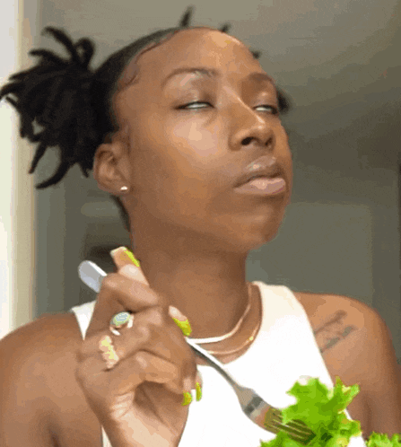 a woman eating a salad with a fork and spoon