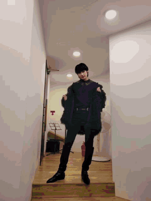 a person standing in a hallway holding a black coat