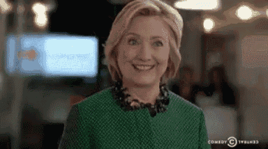 hillary clinton is smiling while wearing a green dress and necklace .