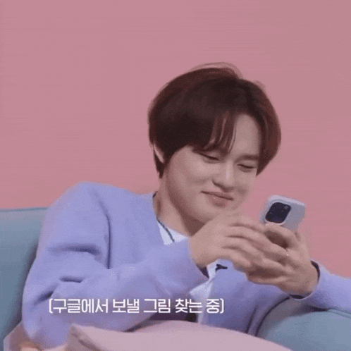a man in a purple sweater is smiling while looking at a cell phone