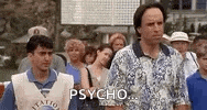 two men are standing next to each other in front of a crowd of people . one man is wearing a vest that says psycho .