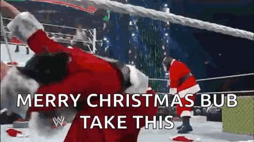 a man in a santa suit is wrestling another man in a boxing ring .