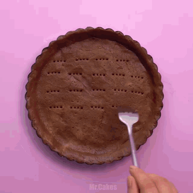 a person is using a fork to fill a pie crust with mr.cakes written on the bottom