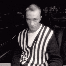 a man in a black and white striped sweater is sitting in a car .