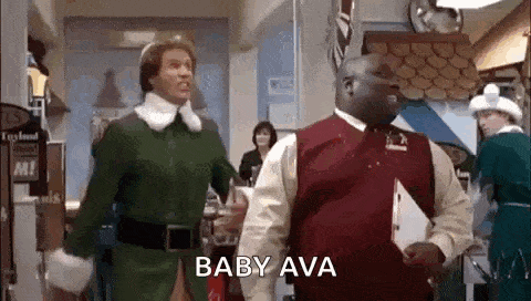 a man in a green elf costume is standing next to a man in a red vest in a room .