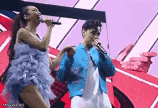 a man and a woman singing into microphones on stage