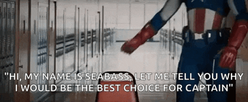 captain america is standing in a hallway with lockers behind him and talking to someone