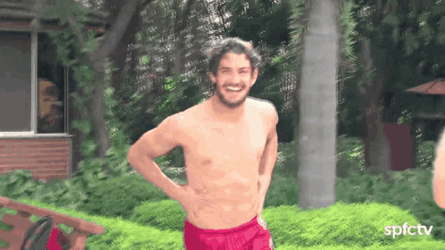 a shirtless man in red swim trunks is smiling in front of a sign that says spfctv