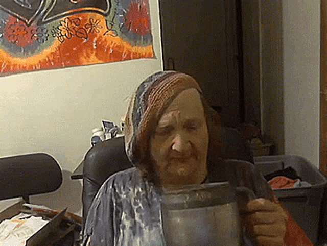 an elderly woman sitting in a chair holding a pitcher
