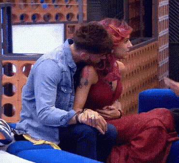 a man and a woman are sitting on a blue couch and kissing