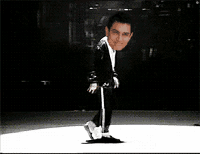 a man in a black suit is dancing on a stage