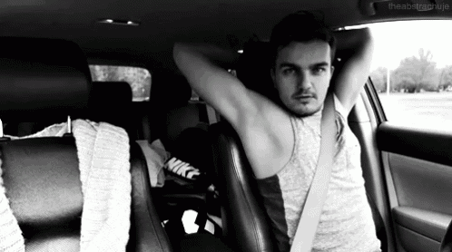 a man is sitting in the back seat of a car with his arms over his head ..