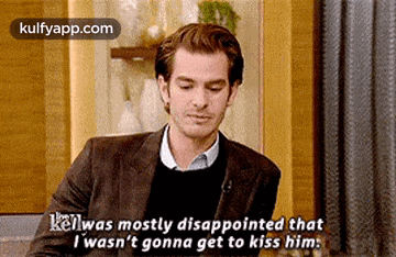a man in a suit and sweater is talking to another man .