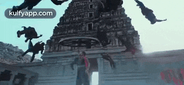 a group of people are flying in the air in front of a building .