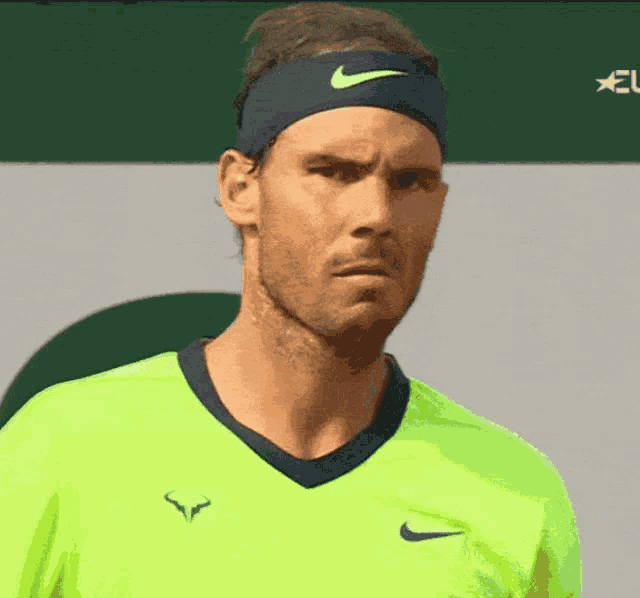 a man wearing a nike headband and a neon green shirt looks at the camera