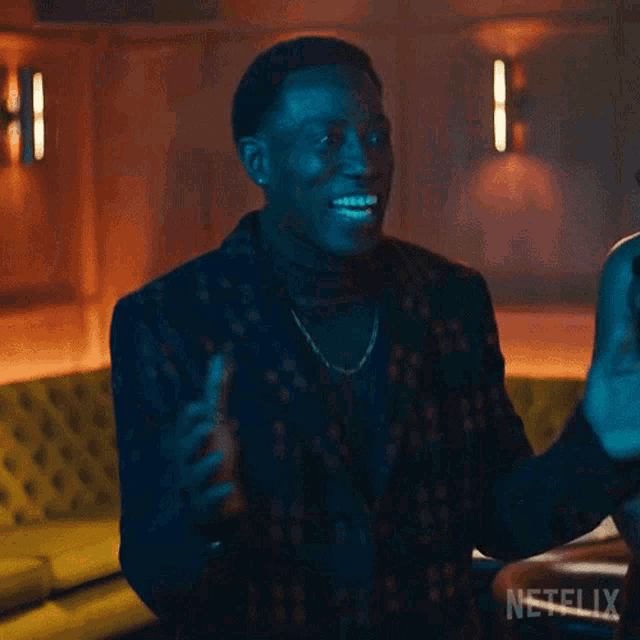 a man in a suit is giving a high five to another man in a room .