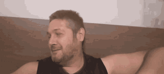 a man with a beard is laying on a bed with his eyes closed