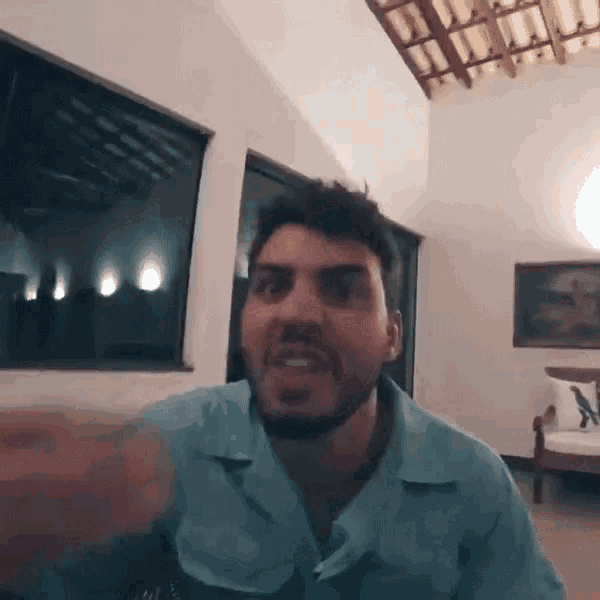 a man with a beard is wearing a blue shirt and making a funny face