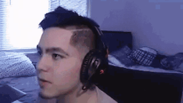 a young man wearing headphones is sitting on a bed in a bedroom .