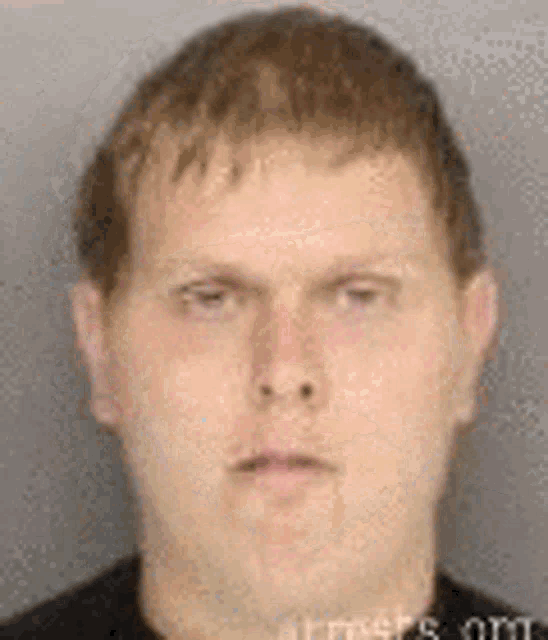 a man in a black shirt is looking at the camera .