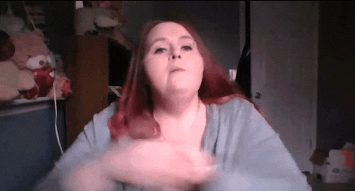 a woman with red hair is making a funny face while sitting in a room with stuffed animals .