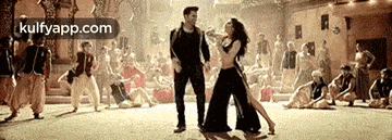 a man and a woman are dancing in front of a crowd in a dance studio .