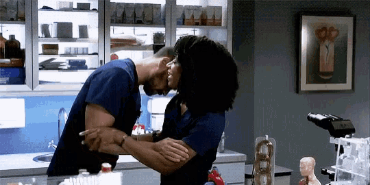 a man and a woman are kissing in a room .