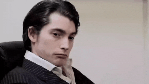 a man in a suit and tie is sitting in a chair and saying mais carrement !