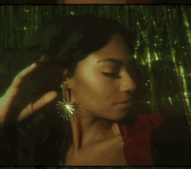 a close up of a woman wearing earrings with a green background
