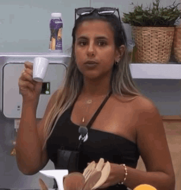a woman in a black top is holding a cup of coffee in her hand .