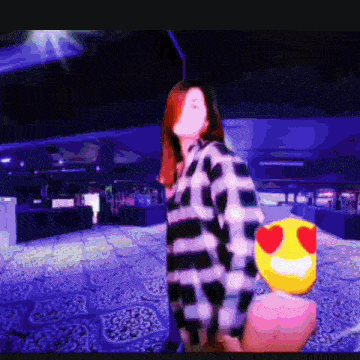 a woman in a plaid shirt is holding a yellow smiley face with hearts on it