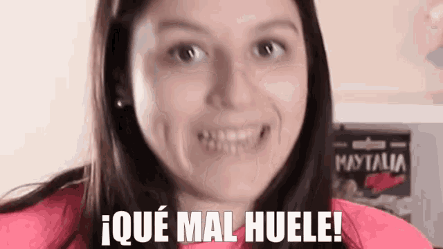 a woman is making a funny face with the words i que mal huele written on her face