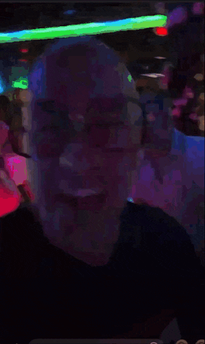 a bald man wearing glasses is smiling in a blurry photo