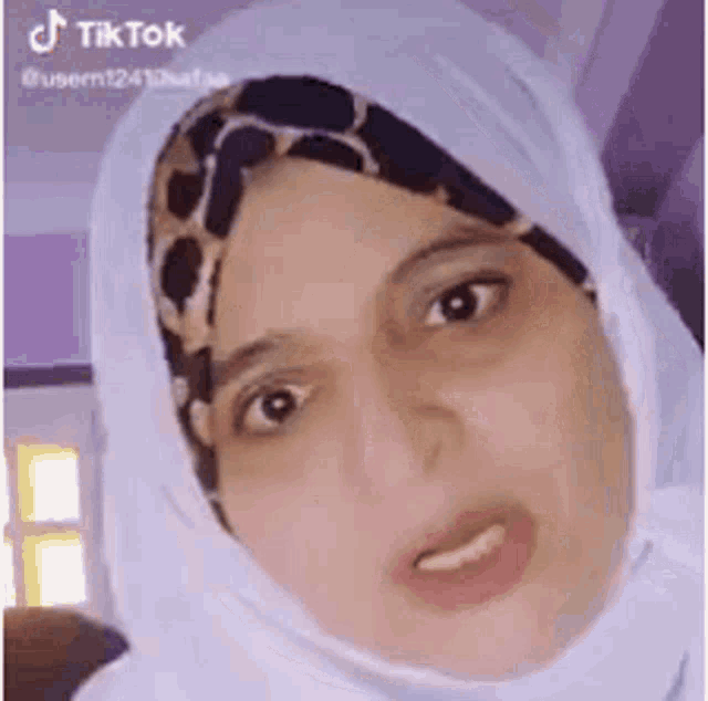 a woman wearing a hijab is making a funny face and looking at the camera .