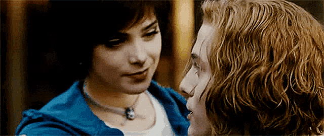 a man and a woman are looking into each other 's eyes . the woman is wearing a blue jacket .