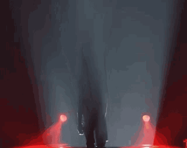 a person walking on a stage with red lights