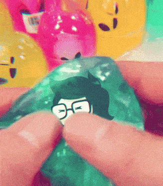 a person is holding a green item with a picture of a person wearing glasses on it