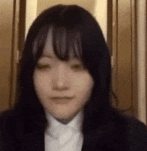 a close up of a woman 's face wearing a suit and tie .