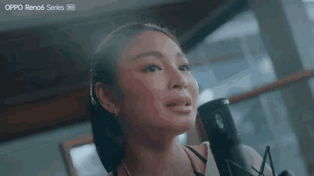 a woman singing into a microphone with the word oppo reno6 series on the bottom right