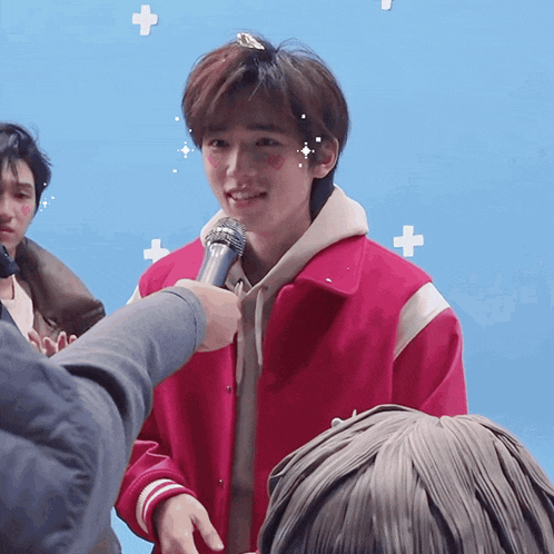 a man in a pink jacket is holding a microphone and smiling