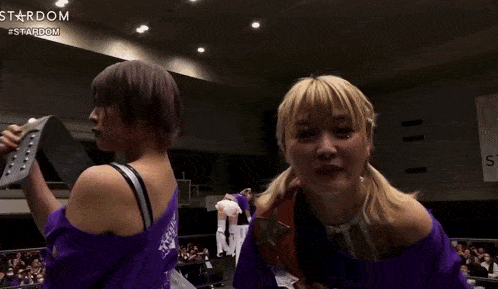 a couple of women are standing next to each other in a ring .